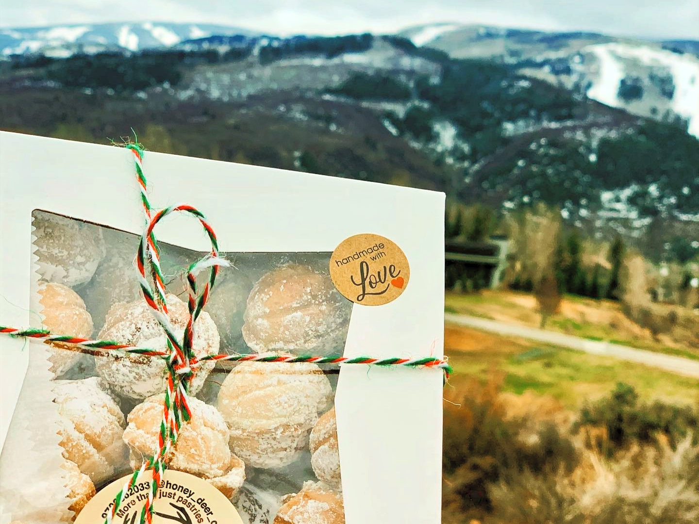A Honey Deer cookie gift box with Colorado mountains behind it