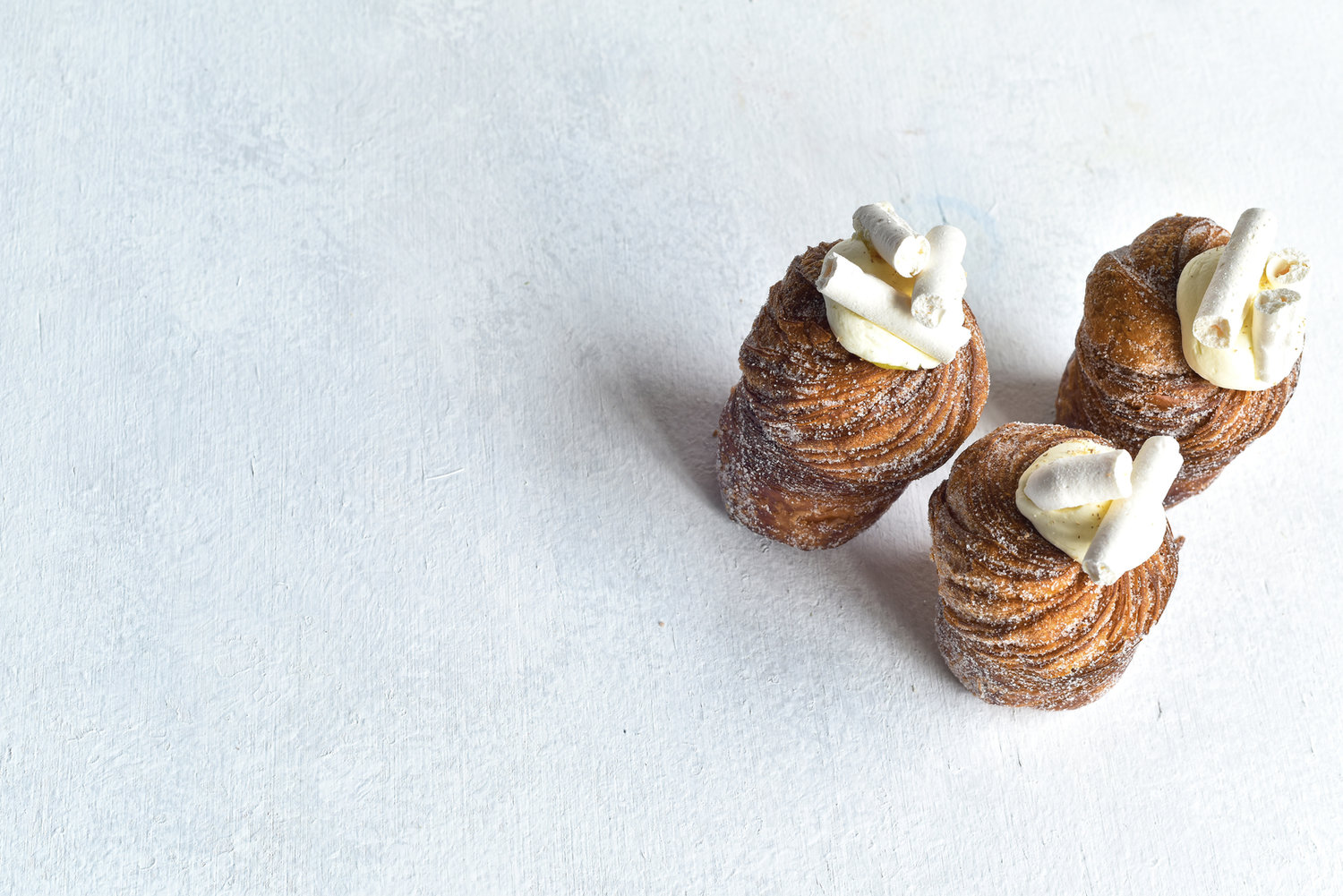 Golden pastries topped with cream on a light table